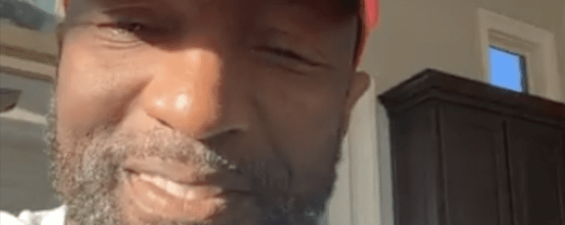 Smiling man wearing a red cap indoors.