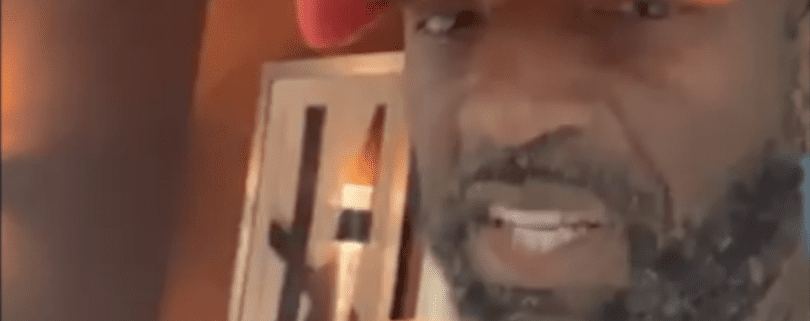 Man wearing red hat indoors, smiling slightly.