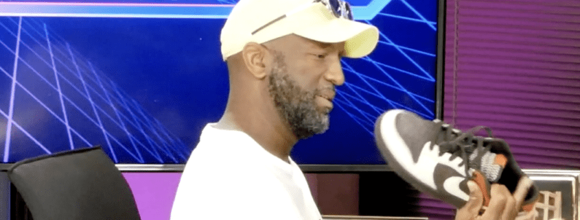 Man examining a sneaker in studio setting.