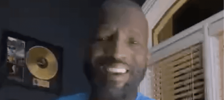Smiling man indoors with gold record background.