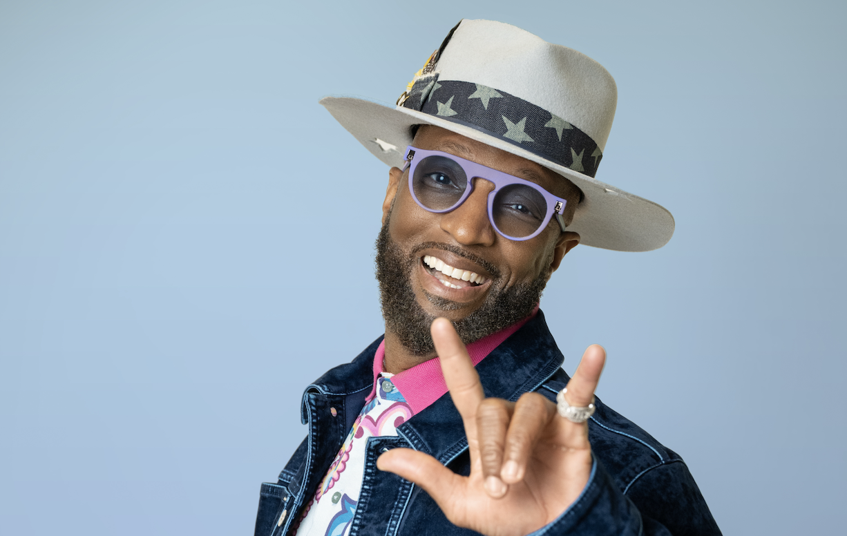 Rickey Smiley Fingers 03.12.25 cropped Man wearing hat and glasses, smiling, gesturing.
